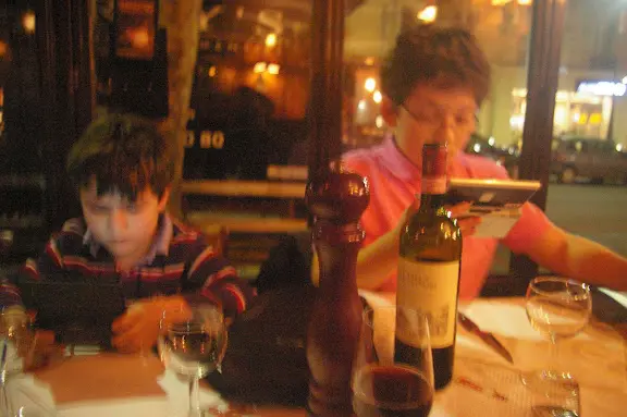 Two people sitting at a table with wine.