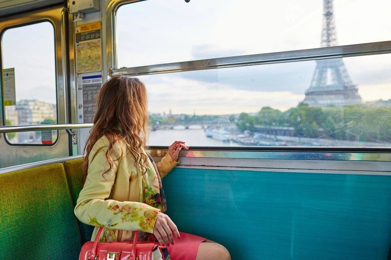 A woman sitting on the side of a bus looking out at the eiffel tower.