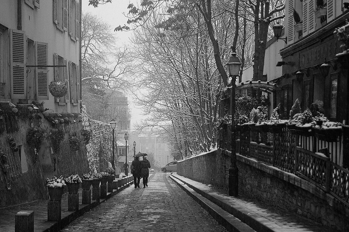 Two people walking down a snowy street in the winter.