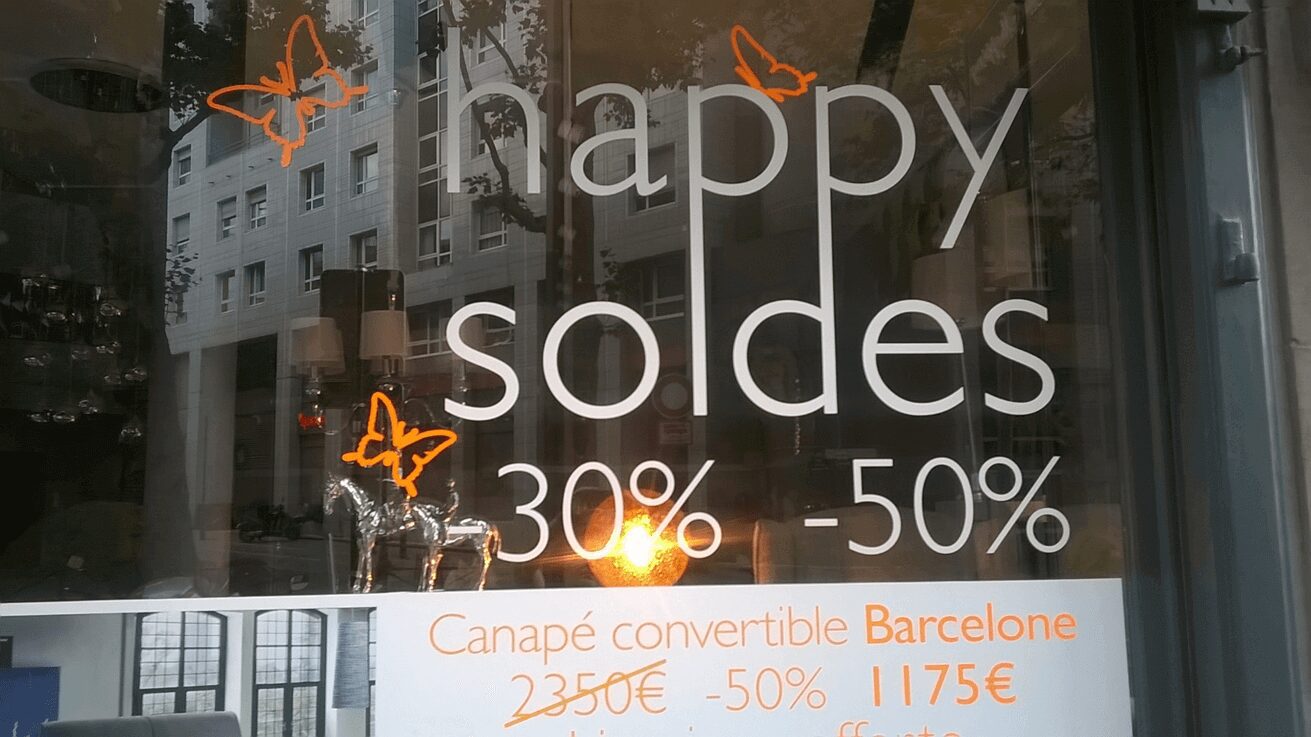 A store window with the words happy soldes in orange.