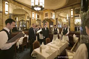 A group of men standing around a table in a restaurant.