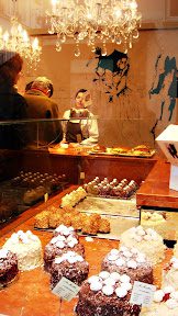 A person is looking at some pastries in the window.