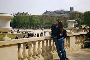 A man and woman kissing on the side of a railing.