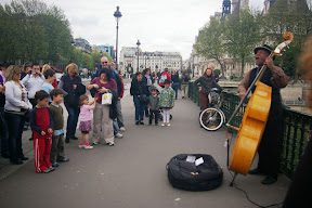 A street performer playing the cello on the sidewalk.
