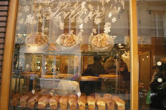 A bakery window with many different pastries on display.