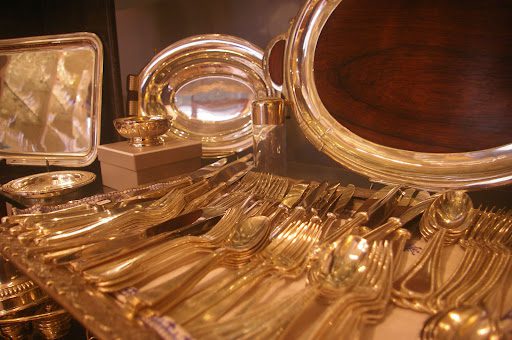 A table with many gold plated silverware and dishes.