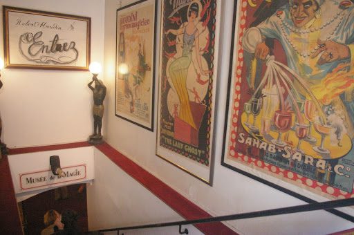 A staircase with posters on the wall and a statue.