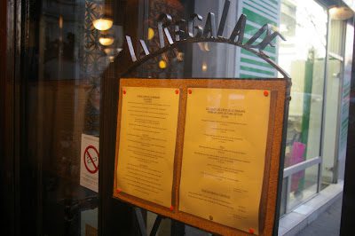 A menu board with knives stuck to it.