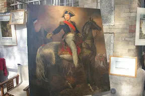A painting of napoleon on horseback in uniform.