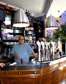 A man standing behind the bar of a restaurant.