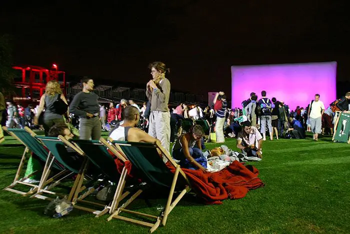 A crowd of people sitting on lawn chairs.
