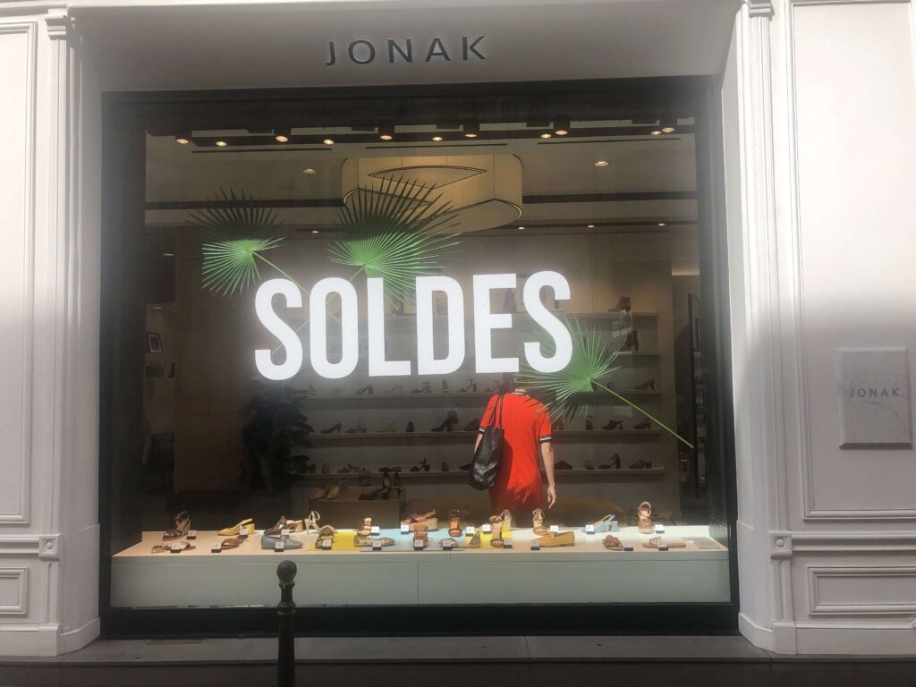 A woman is standing in front of a store window.