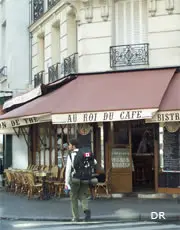 A person walking in front of an outdoor cafe.