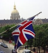 A british flag flying in front of the dome of an old building.