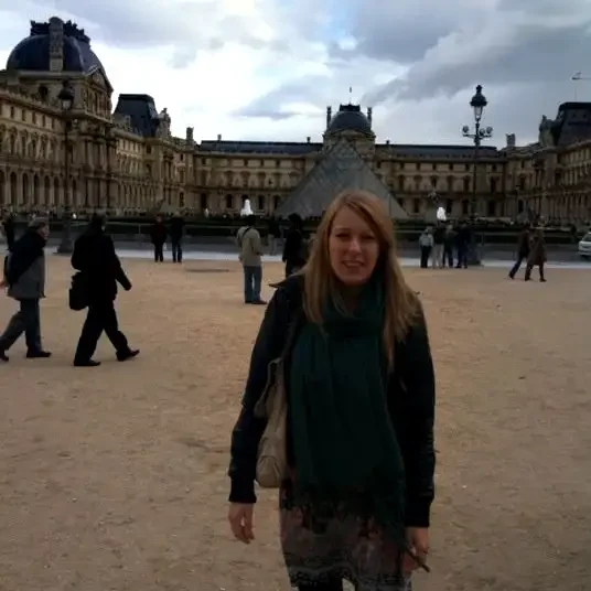 A woman standing in front of the louvre museum.
